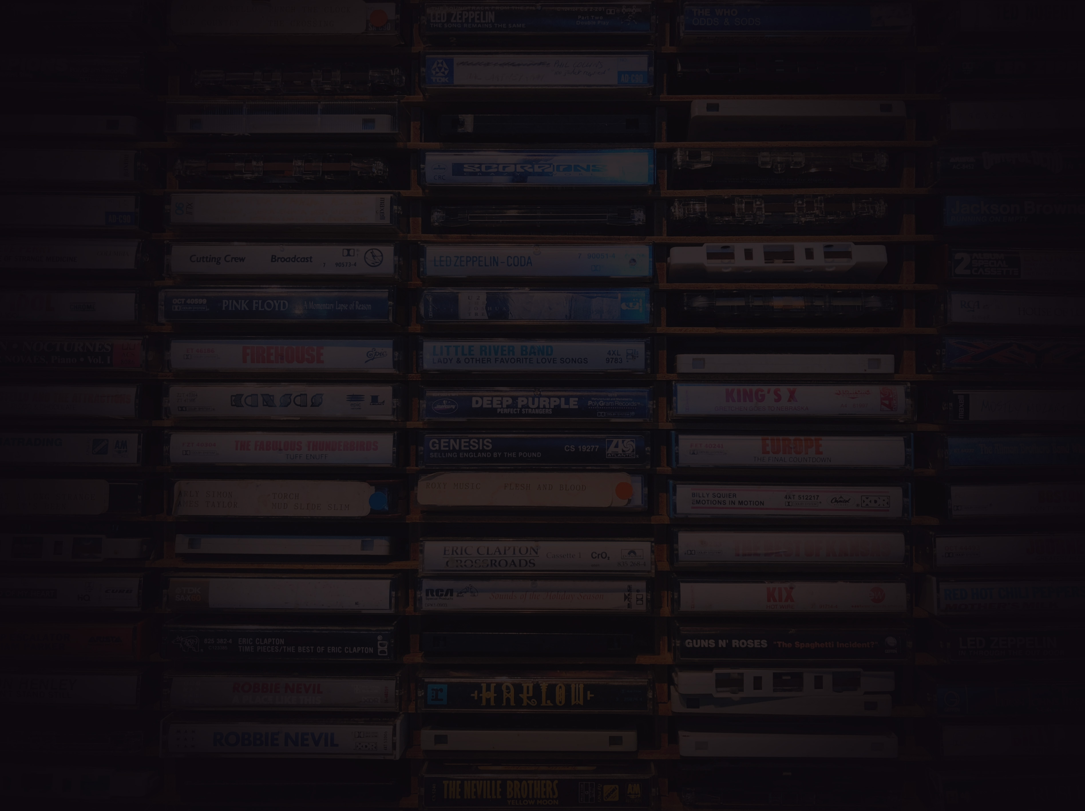 A wall of classic rock and pop cassette tapes from the 1980s.